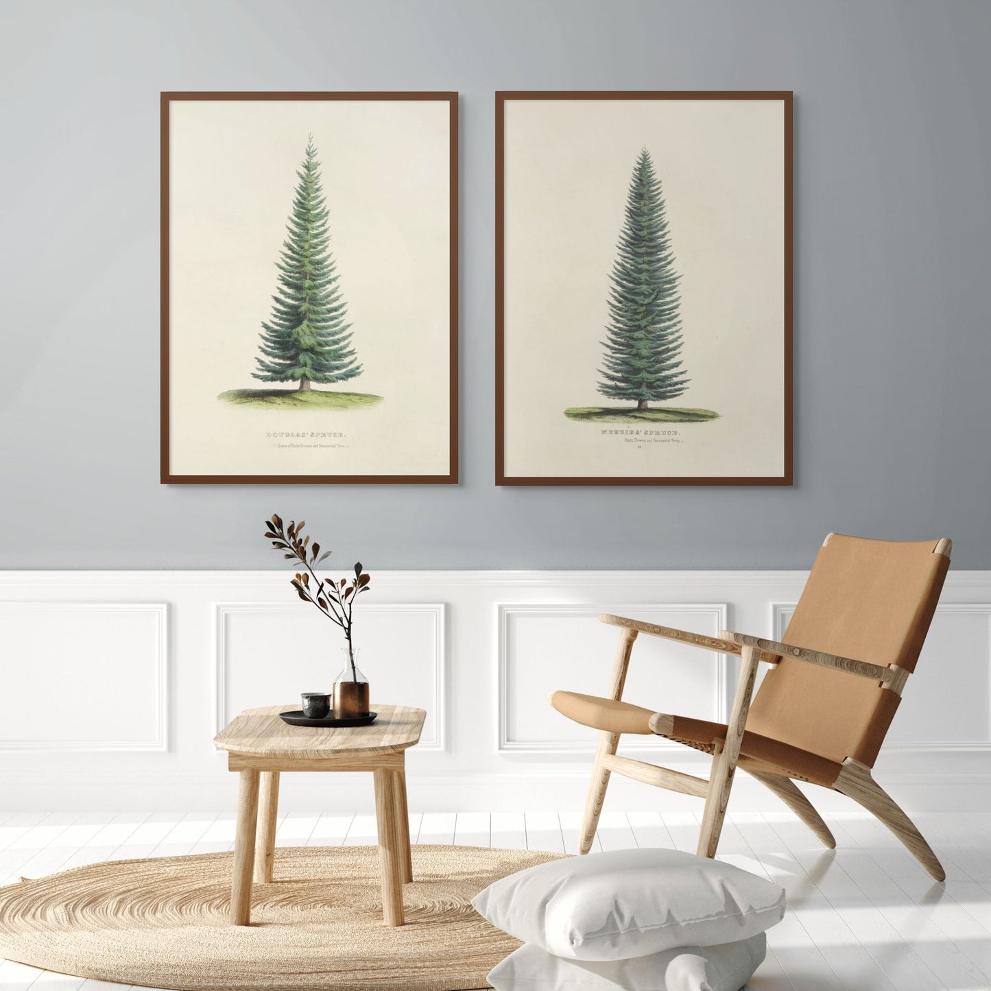 Two framed tree prints on a wall above a wooden side table and chair.
