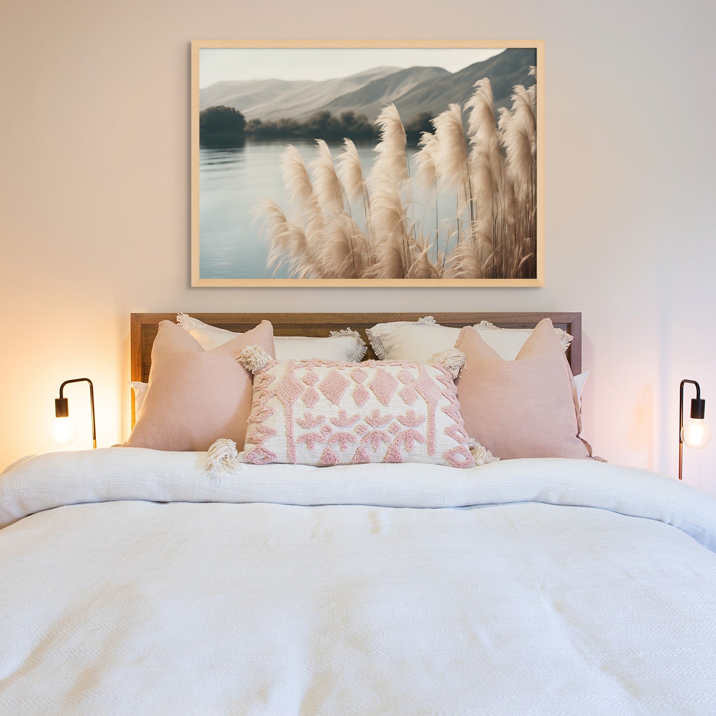 A unique photograph print on canvas of soft and fluffy pampas grass by the lake near the mountains. A calm and serene landscape. Displayed above a bet with soft pink pillows.