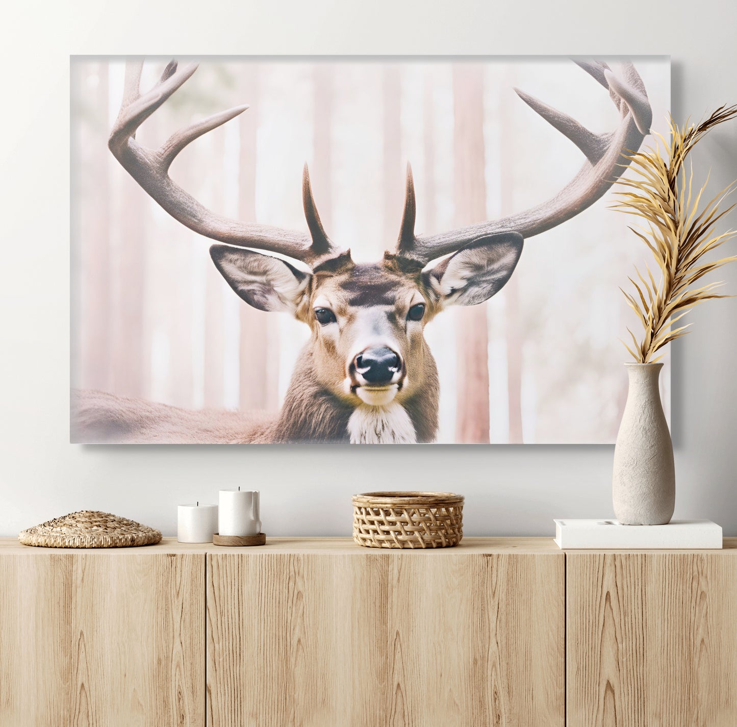 A unique artwork of a deer with long antlers in soft, neutral colors. The background is a light color redwood forest. A print on canvas hung over a light wood hutch.