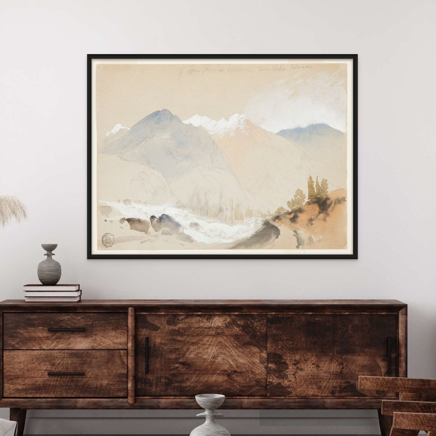 vintage artwork by Thomas Moran of an Alpine Pass. Featuring soft colors of blue and sandy beige displayed on a wall above a wood hutch in a living room